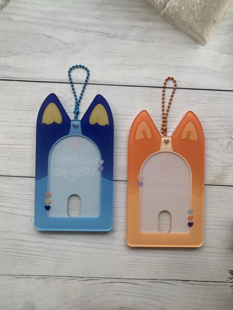 May include: Two plastic card holders with a cat-shaped design. The holder on the left is blue with the text "Love you because" and the holder on the right is orange.