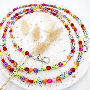 Könnte beinhalten: Ein farbenfrohes Perlenband mit einem silbernen Verschluss. Die Perlen sind in Form von Smileys und in verschiedenen Farben, darunter Rot, Orange, Gelb, Grün, Blau, Lila und Pink.