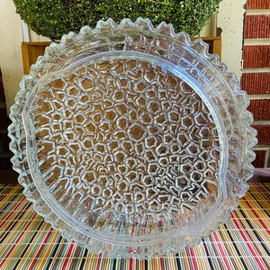 May include: A clear glass serving dish with a scalloped edge and a textured, honeycomb-like pattern on the bottom.