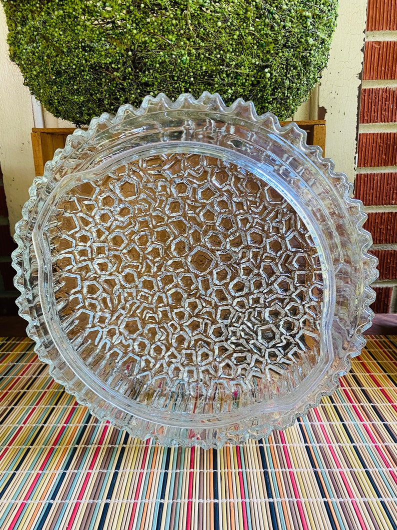 May include: A clear glass serving dish with a scalloped edge and a textured, honeycomb-like pattern on the bottom.