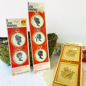 May include: Several vintage picture frames are displayed. Two packages of "Link Frames" with gold-colored frames and black silhouette portraits are visible. A package of "Craft & Photo Frames" with cross-stitch designs is also present.