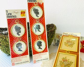 May include: Several vintage picture frames are displayed. Two packages of "Link Frames" with gold-colored frames and black silhouette portraits are visible. A package of "Craft & Photo Frames" with cross-stitch designs is also present.