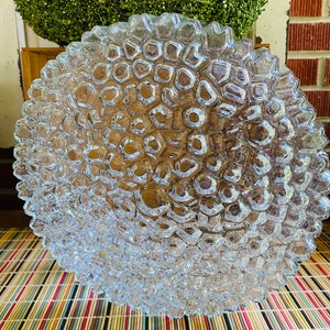 May include: A clear glass bowl with a textured, bubble-like design. The bowl is round and has a wide rim.