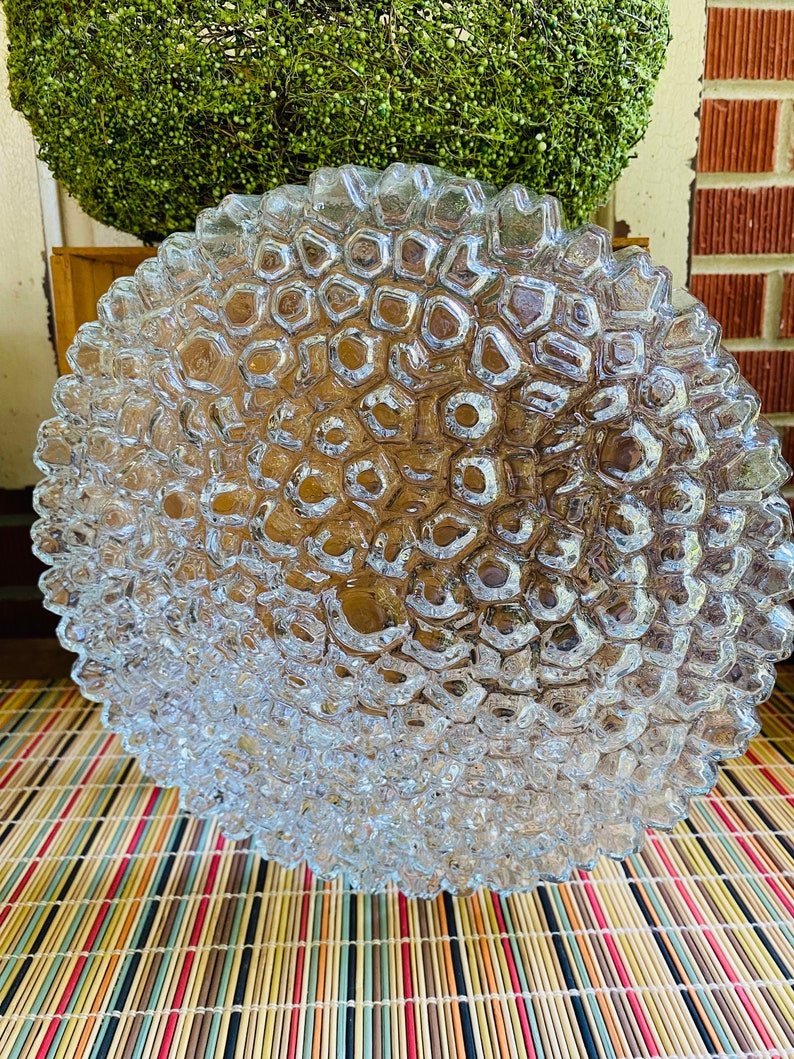May include: A clear glass bowl with a textured, bubble-like design. The bowl is round and has a wide rim.