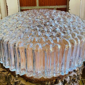 May include: A clear glass ceiling light fitting with a textured, bubble-like design. The light fitting is round and has a ribbed edge.