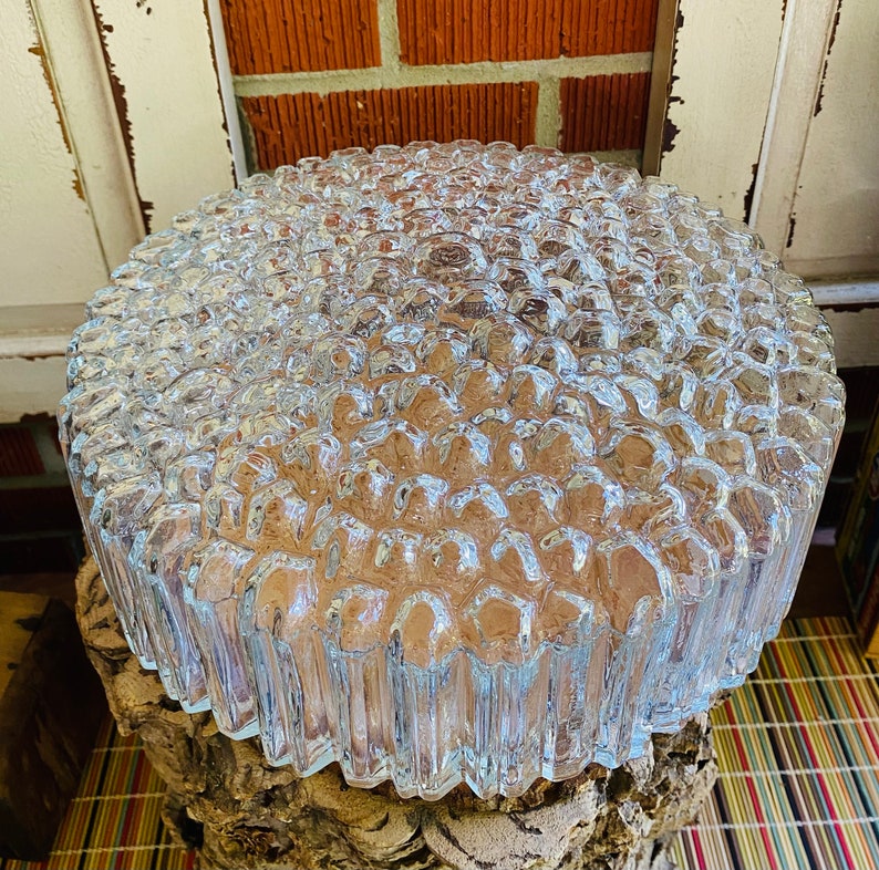 May include: A clear glass ceiling light fitting with a textured, bubble-like design. The light fitting is round and has a diameter of approximately 30 cm.