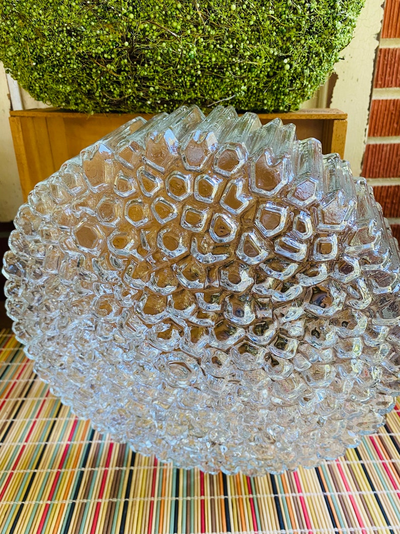 May include: A clear glass ceiling light fitting with a textured, honeycomb-like design. The light fitting is round and has a diameter of approximately 30 cm.