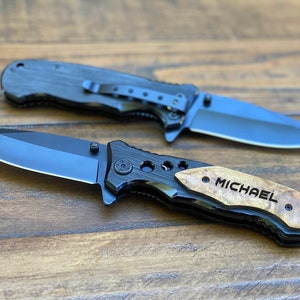 May include: Two black pocket knives with wood handles. The handle of one knife is engraved with the name "MICHAEL".