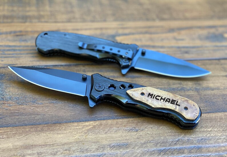 May include: Two black pocket knives with wood handles. The handle of one knife is engraved with the name "MICHAEL".