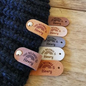 May include: Six brown leather tags with a rainbow and the text "This belongs to Henry" on each tag.