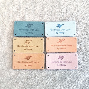 May include: Six rectangular labels in pastel shades of blue, beige, and pink. Each label is printed with the text "Handmade with Love by Henry" and a heart-shaped design with a needle and thread.