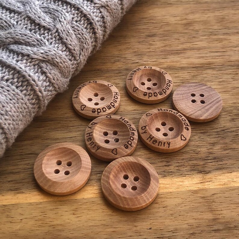 May include: Six wooden buttons with four holes each. The buttons are engraved with the text "Handmade by Henry" and a heart symbol.