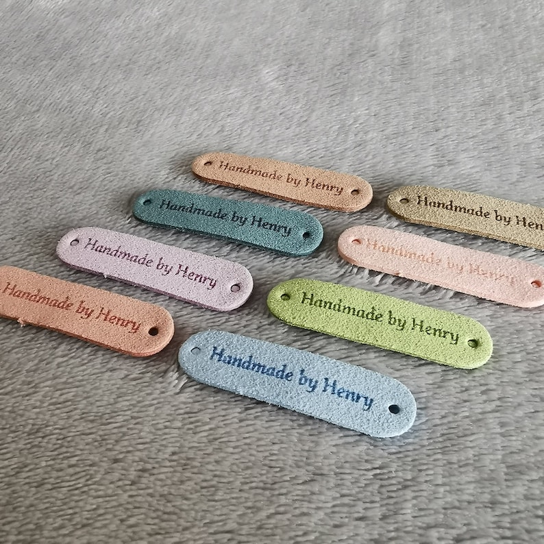 Peut inclure: Huit &eacute;tiquettes en tissu color&eacute;es avec le texte "Handmade by Henry" en &eacute;criture cursive.