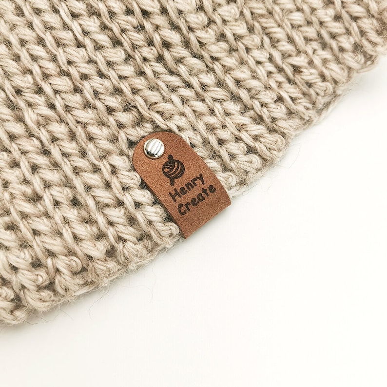 May include: A beige knitted hat with a brown leather tag that says "Henry Create" and features a small yarn ball icon.