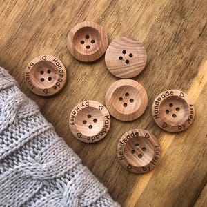 May include: Six wooden buttons with the text "Handmade by Henry" and a heart symbol engraved on each button.