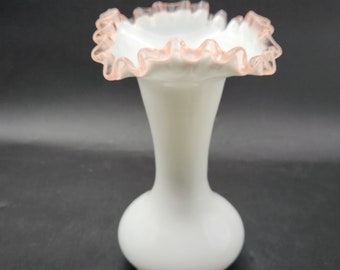 May include: A white milk glass vase with a pink ruffled top.