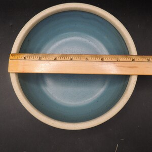 May include: A light blue ceramic bowl with a white rim. The bowl is approximately 10 inches in diameter.