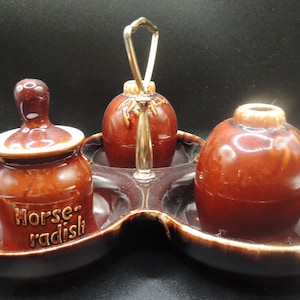 May include: A brown ceramic condiment set with a handle. The set includes three containers, one labeled "Horse-radish".