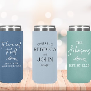 May include: Three blue, light blue, and green can coolers with white text. The first cooler says "To have and to hold" and "And to keep your drink cold". The second cooler says "Cheers to Rebecca and John". The third cooler says "The Johnsons Est. 07.12.26".