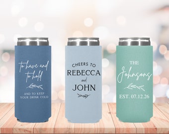 May include: Three can coolers in blue, light blue, and green with white text. The first cooler says "To have and to hold" and "And to keep your drink cold". The second cooler says "Cheers to Rebecca and John". The third cooler says "The Johnsons Est. 07.12.26".