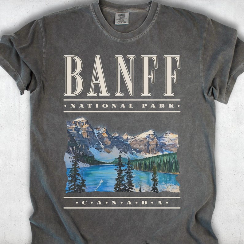 A dark grey Comfort Colors t-shirt with off-white vintage text reading "Banff National Park" and "CANADA," with a graphic illustration of Moraine Lake.