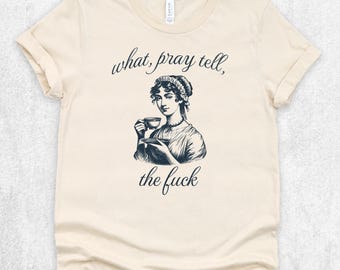 May include: A cream-colored short-sleeve t-shirt featuring a black ink-style illustration of a person in historical attire holding a teacup and saucer. The text above and below the illustration reads, what, pray tell, the fuck.