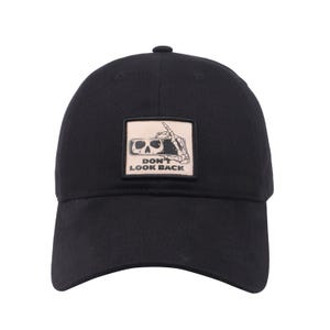 May include: Black baseball cap with a curved brim. The cap features a square patch with a skull wearing glasses and a skeleton hand giving the middle finger. The text "DON'T LOOK BACK" is below the graphic.