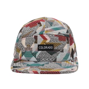 May include: A five-panel cap with a colorful geometric pattern in shades of red, yellow, green, and blue. The cap features a small rectangular patch with the word "COLORADO" in white letters.