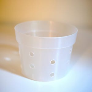 May include: A white plastic cheese mold with holes for draining whey. The mold is cylindrical and has a smooth, rounded bottom.