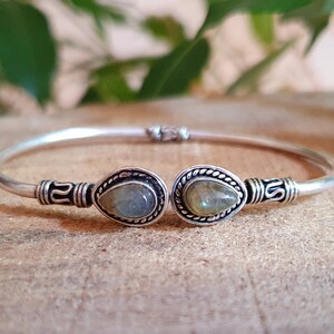 Puede incluir: Un brazalete de plata con dos piedras de labradorita en forma de lágrima engastadas en plata.