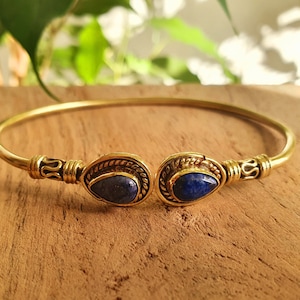 Peut inclure: Un bracelet jonc en or avec deux pierres de lapis-lazuli en forme de larme serties dans des montures en laiton ornées.