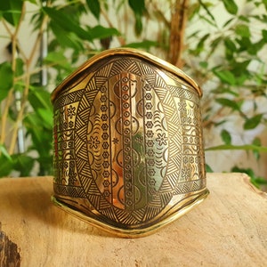 Peut inclure: Un bracelet en métal doré avec un motif géométrique complexe. Le bracelet est incurvé et présente une finition lisse et polie.