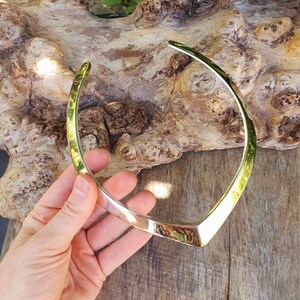 May include: A silver metal choker necklace with a V-shaped design.