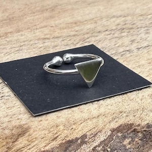 May include: A silver ring with a triangular shaped top. The ring is open and adjustable.