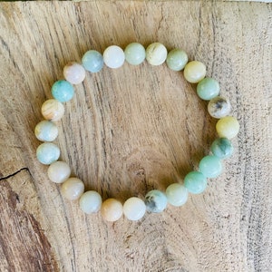 May include: A bracelet made of light green, white, and yellow beads. The beads are round and have a natural, polished look.