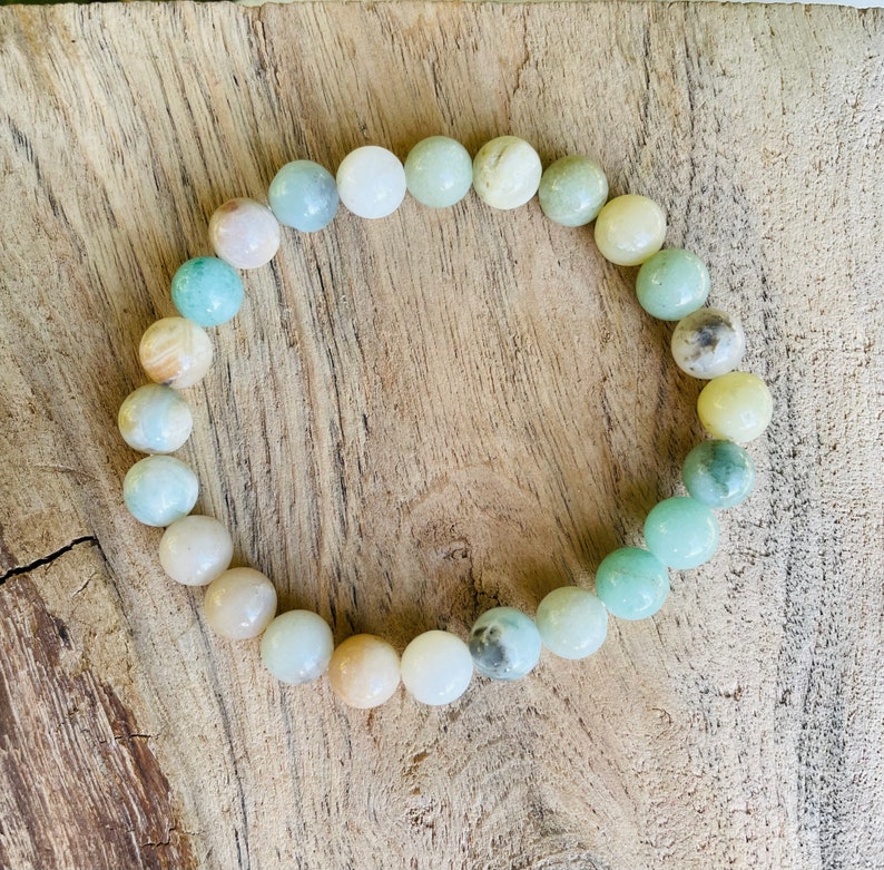 May include: A bracelet made of light green, white, and yellow beads. The beads are round and have a natural, polished look.