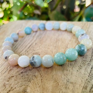 May include: A green, white, and pink gemstone bracelet with round beads. The bracelet is made of natural stones and is a beautiful and unique piece of jewelry.
