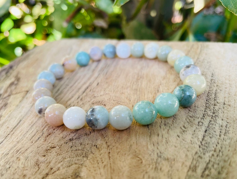 May include: A green, white, and pink gemstone bracelet with round beads. The bracelet is made of natural stones and is a beautiful and unique piece of jewelry.