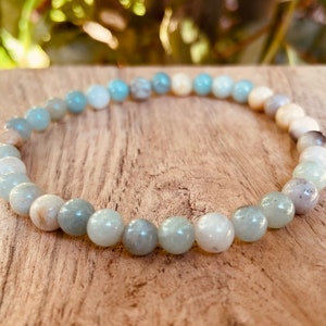 May include: A light blue and white beaded bracelet made of natural stones. The bracelet is made of round beads and is approximately 7 inches in length.