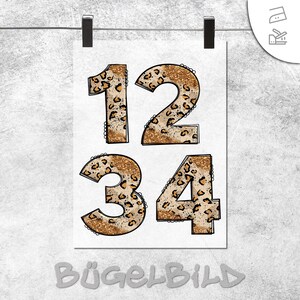 Könnte beinhalten: Ein weißes Papier mit den Zahlen 1, 2, 3 und 4. Die Zahlen haben ein Leopardenmuster mit Goldglitzer-Effekt. Das Wort "BÜGELBILD" ist unten aufgedruckt.