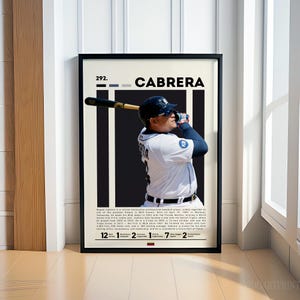 May include: Framed art print featuring baseball player Miguel Cabrera in a batting pose. The print has a black frame and a white background with black vertical stripes. The name "CABRERA" is displayed in bold white letters.