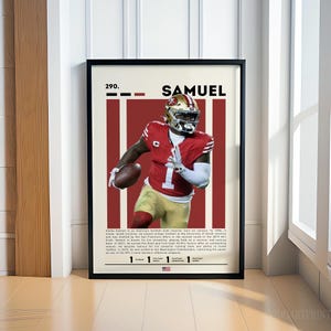 May include: Framed poster of a football player in a red and gold uniform, with the name "SAMUEL" at the top. The poster has a white background with red vertical stripes and includes text about the player's career.