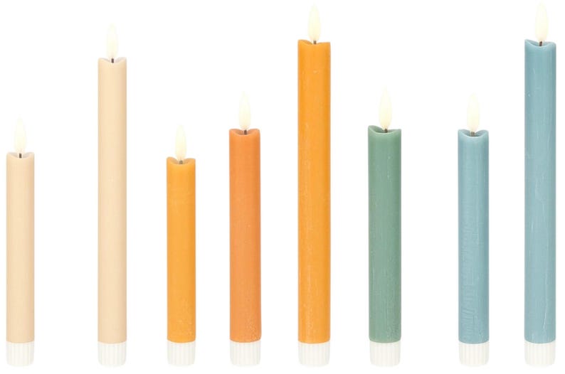 May include: A collection of eight colorful taper candles in varying heights. The candles are in shades of cream, yellow, orange, green, and blue. Each candle has a white base and a flickering flame at the top.