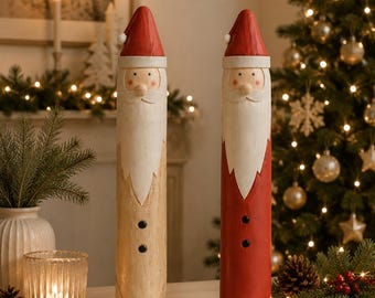May include: Two tall, cylindrical wooden Santa Claus figurines. One figure features a natural light wood finish on the lower body, while the other is painted red. Both have white beards, red pointed hats with white pom-poms, and two black buttons.