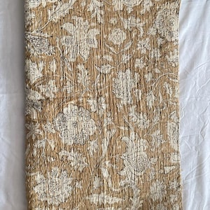 May include: A brown and white floral kantha quilt with a traditional Indian design. The quilt is made of cotton and is hand-stitched.