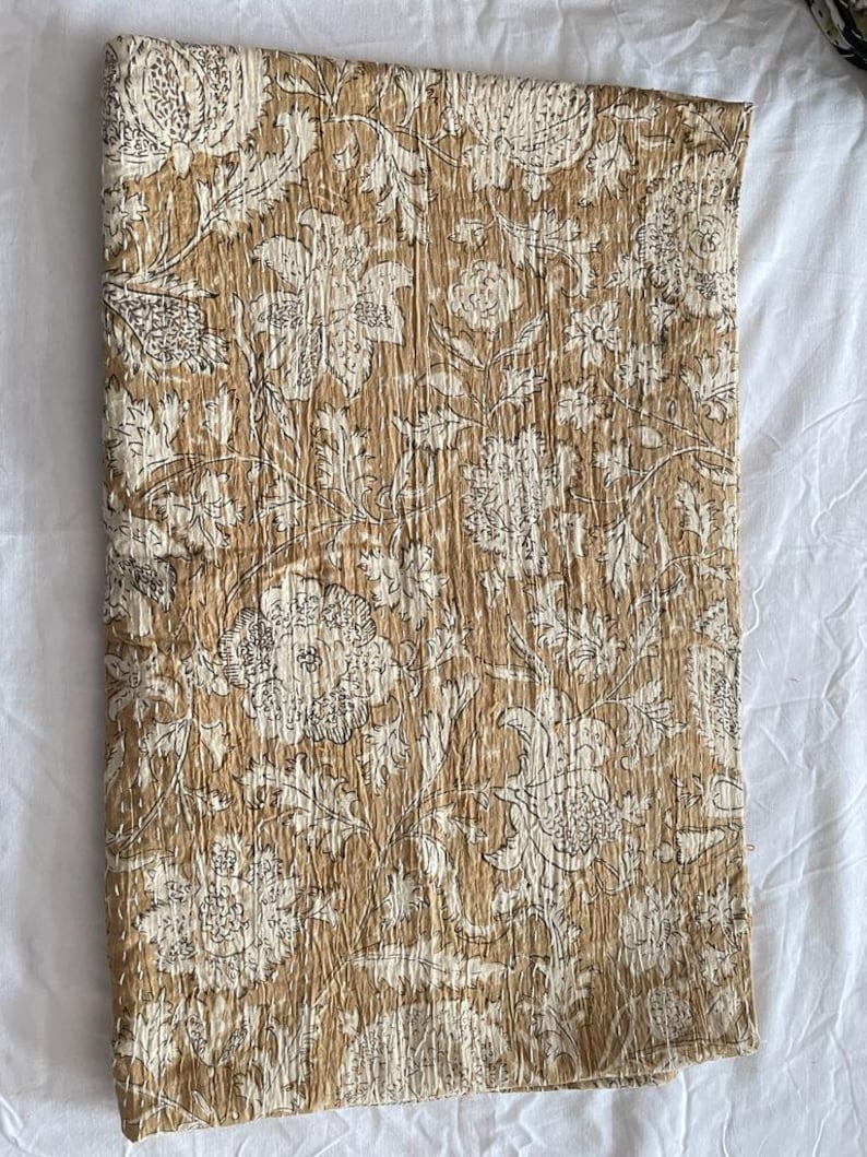 May include: A brown and white floral kantha quilt with a traditional Indian design. The quilt is made of cotton and is hand-stitched.