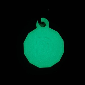 May include: A green glow-in-the-dark plastic tag with a rounded octagonal shape and a hole at the top for attaching a string or chain.