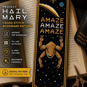 May include: Black cross-stitch bookmark with a gold border, featuring a space-themed design. The bookmark has the word "AMAZE" repeated three times, a shooting star, and a figure with its arms raised. The bookmark is a digital pattern.