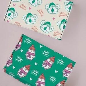 May include: Two gift boxes with Christmas wrapping paper. One box has a green background with a white penguin wearing a red hat and pink scarf. The penguin has a speech bubble that says "Merry X-Mas". The other box has a cream background with a green koala wearing a red hat. The koala has a speech bubble that says "Merry Christmas".