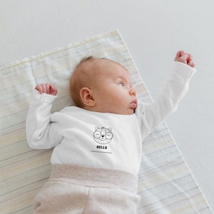 Little baby wearing a shirt with baby bear drawing on it